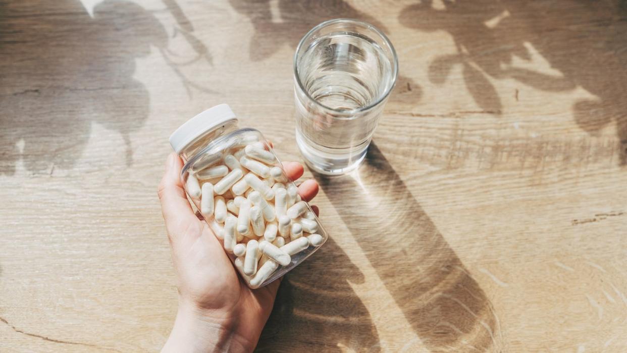 woman doctor nutritionist hands in white shirt with omega 3, vitamin d capsules with green vegan food the doctor prescribes a prescription for medicines and vitamins at the clinic