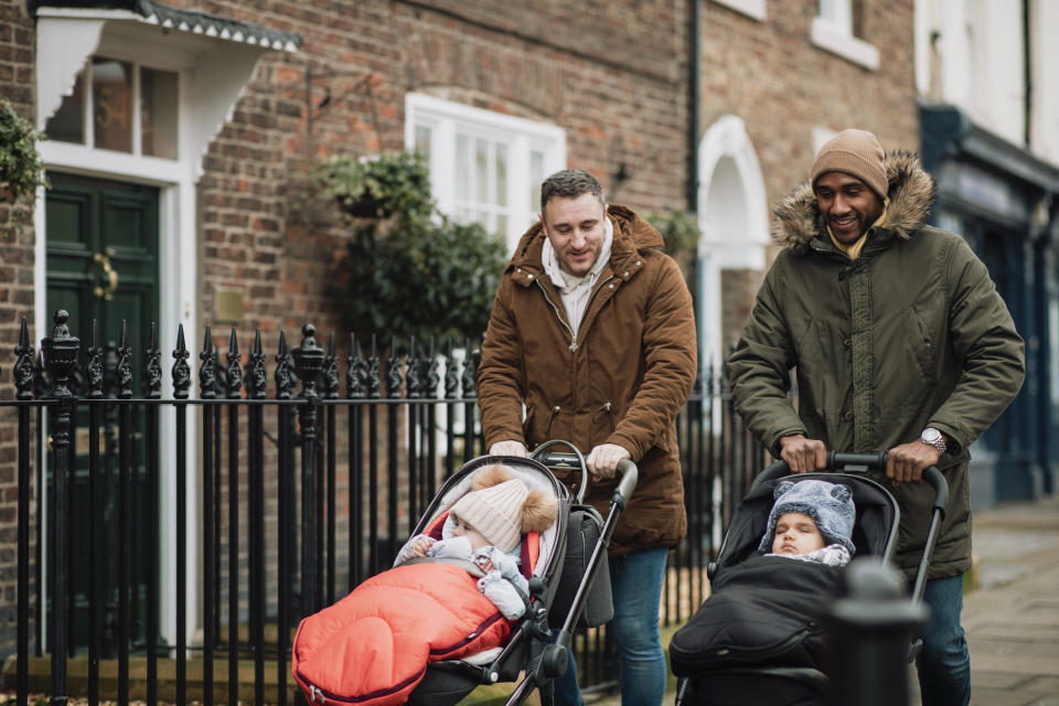 Men pushing their babies in strollers on a sidewalk