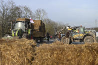 Farmers install hay bales on a highway near Paris's main airport, Monday, Jan. 29, 2024 near Roissy-en-France, north of Paris. Protesting farmers were encircling Paris with tractor barricades and drive-slows on Monday, using their lumbering vehicles to block highways leading to France's capital to pressure the government over the future of their industry, which has been shaken by repercussions of the Ukraine war.(AP Photo/Matthieu Mirville)