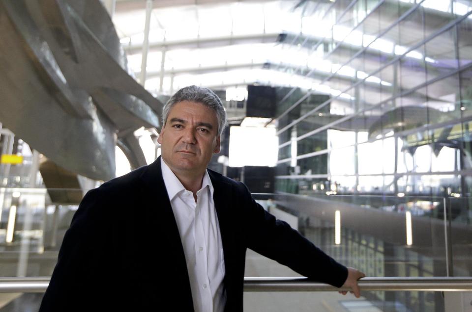 Luis Vidal, Concept and Lead Architect poses for a photograph at the new Heathrow Terminal 2 in London, Wednesday, April 23, 2014, next to the sculpture 'Slipstream', left, by artist Richard Wilson which will be the longest permanent sculpture in Britain, measuring 78 metres and weighing 77 tonnes. The 2.5 billion pound ($4.2 billion) new Terminal 2 is due to open to the public in June after 5-years in development, to handle the anticipated 20 million passengers per year. (AP Photo/Kirsty Wigglesworth)