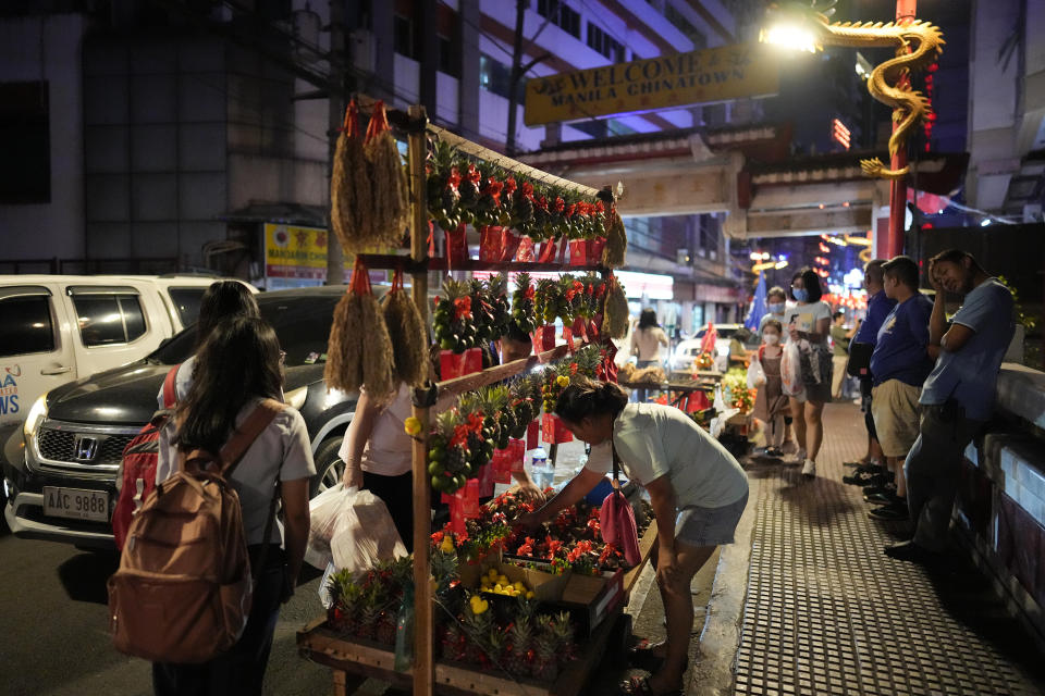 A vendor sells fruits with lucky charms for the coming Chinese New Year at Binondo district, said to be the oldest Chinatown in the world, in Manila, Philippines on Tuesday, Feb. 6, 2024. Crowds are flocking to Manila's Chinatown to usher in the Year of the Wood Dragon and experience lively traditional dances on lantern-lit streets with food, lucky charms and prayers for good fortune. (AP Photo/Aaron Favila)