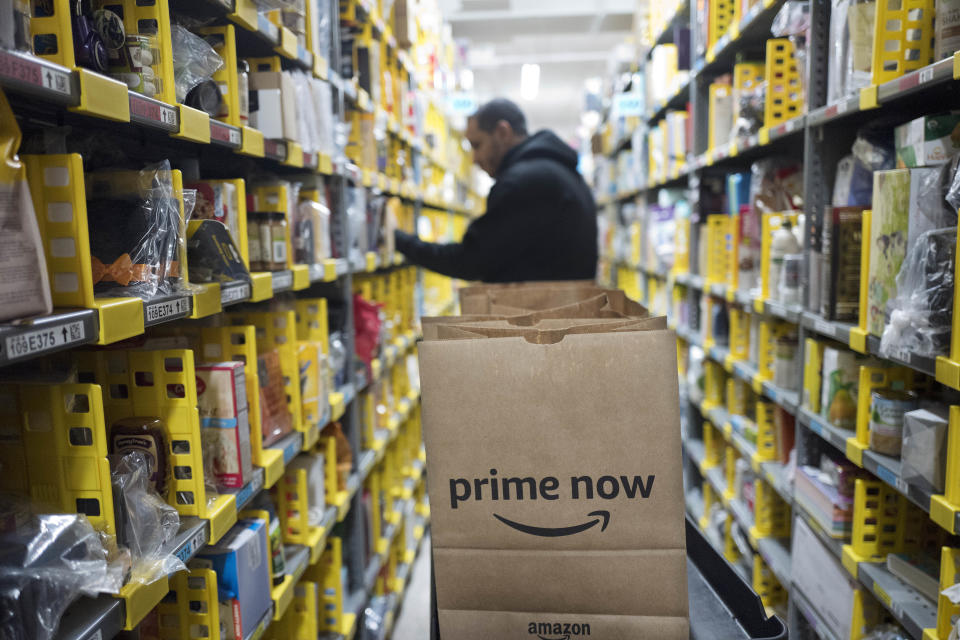 FILE - In this Dec. 20, 2017, file photo, a clerk reaches to a shelf to pick an item for a customer order at the Amazon Prime warehouse in New York. Amazon's Prime Day starts July 16, 2018, and will be six hours longer than last year's and will launch new products. Amazon hopes to keep Prime attractive for current and would-be subscribers after raising the annual membership fee by 20 percent to $119 and to $12.99 for the month-to-month option.. (AP Photo/Mark Lennihan, File)