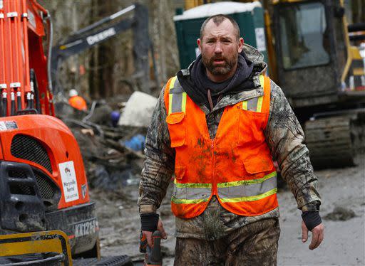 A weary searcher heads out of the west side of the mudslide site with a small saw on Highway 530 near mile marker 37  in Arlington, Wash., on Sunday, March 30, 2014. Periods of rain and wind have hampered efforts the past two days, with some rain showers continuing today. Last night, the confirmed fatalities list was updated to 18, with the number of those missing falling from 90 to 30. (AP Photo/Rick Wilking, Pool)