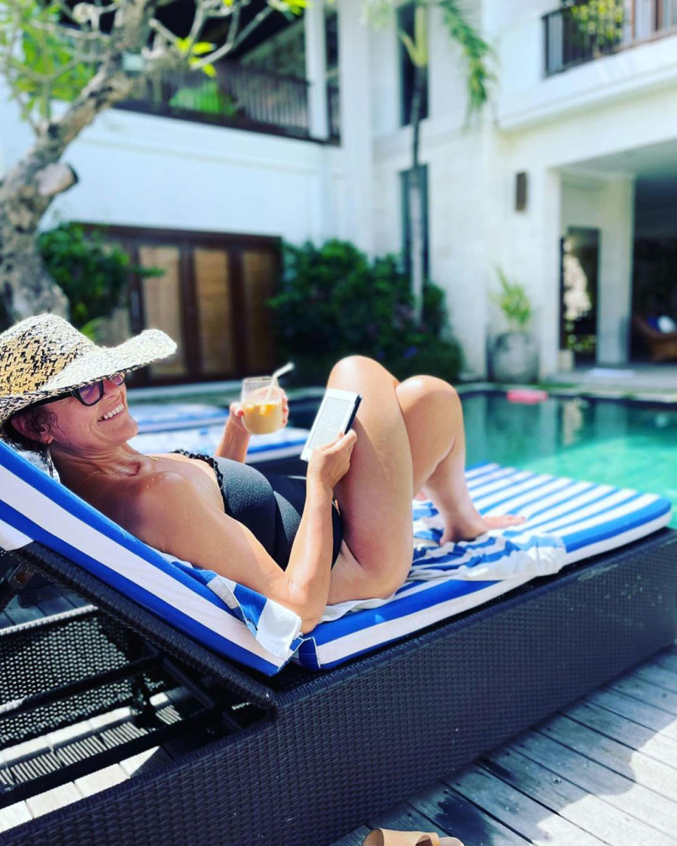 Chrissie Swan lounging by a pool in Bali while wearing a swimsuit