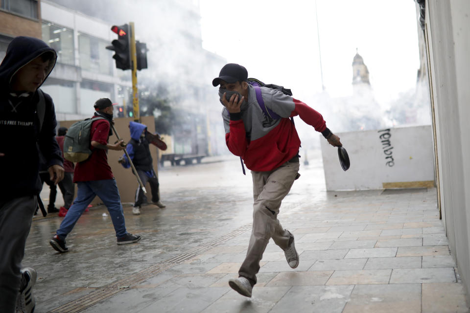 Anti-government protesters run during clashes with police in downtown Bogota, Colombia, Friday, Nov. 22, 2019. Labor unions and student leaders called on Colombians to bang pots and pans Friday evening in another act of protest while authorities announced three people had died in overnight clashes with police after demonstrations during a nationwide strike. (AP Photo/Ivan Valencia)