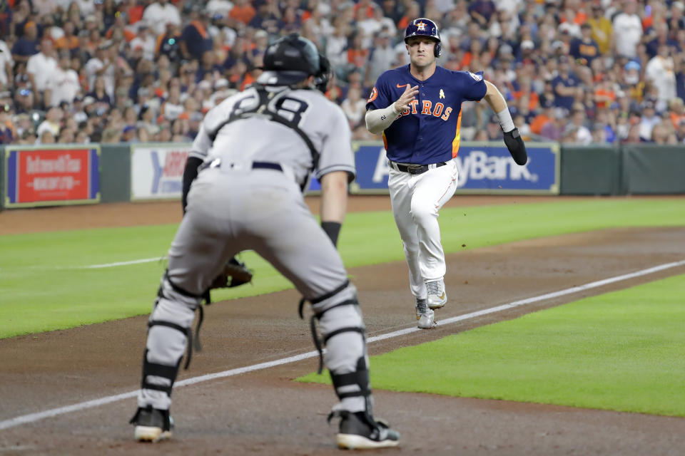 After tagging up at third base, Houston Astros Alex Bregman, right, heads for home plate on the sacrifice fly by Kyle Tucker to score as New York Yankees catcher Austin Wells, left, waits for a throw during the first inning of a baseball game Sunday, Sep. 3, 2023, in Houston. (AP Photo/Michael Wyke)