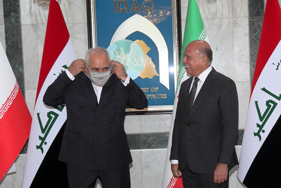 Iranian Foreign Minister Mohammad Javad Zarif, left, wearing a mask to help prevent the spread of the coronavirus is welcomed by Iraqi counterpart, Fouad Hussein, upon his arrival to Baghdad, Iraq, Monday, April 26, 2021. (AP Photo/Khalid Mohammed)