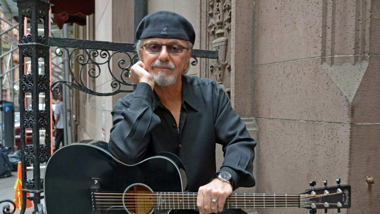  Dion holding a guitar sitting on steps. 