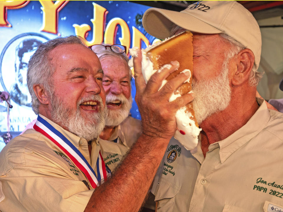 In this photo provided by the Florida Keys News Bureau, Zach Taylor, the 2021 "Papa" Hemingway Look-Alike Contest winner, shoves birthday cake into the face of 2022 winner Jon Auvil, Thursday, July 20, 2023, on the eve of Ernest Hemingway's 124th birthday anniversary, at Sloppy Joe's Bar in Key West, Fla. The birthday commemoration preceded the first round of the 2023 Hemingway Look-Alike Contest, a highlight of the island's annual Hemingway Days festival. The famed American author lived and wrote in Key West for most of the 1930s. (Andy Newman/Florida Keys News Bureau via AP)