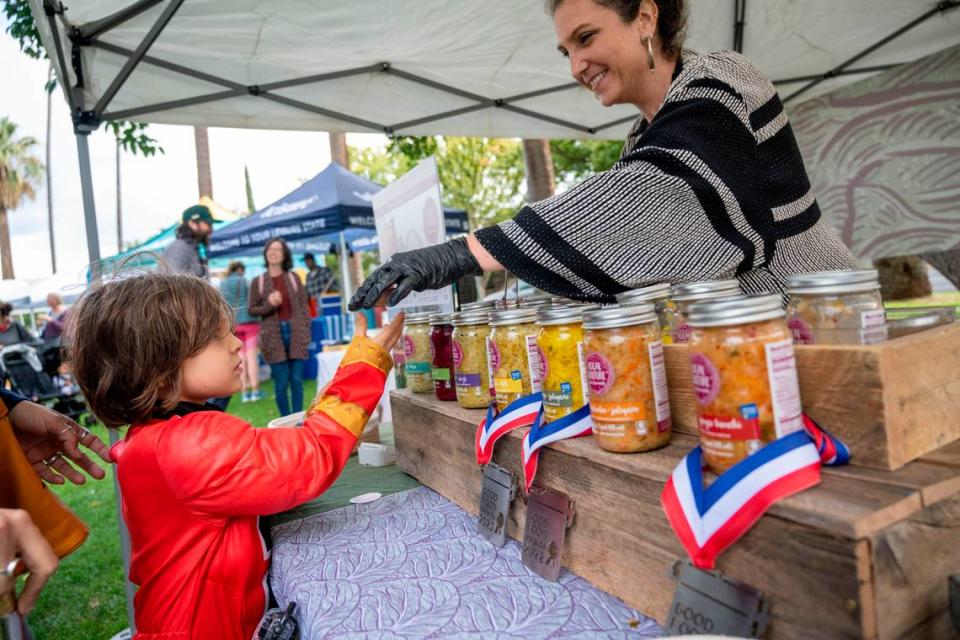 Dressed as a Power Ranger, Hugh Davis, 5, of Sacramento, gets a sample of fermented foods from Elissa Wolf Blank, co-owner of Local Culture of Grass Valley on Saturday during the 50th anniversary celebration of the Sacramento Natural Foods Co-op at Winn Park.