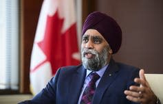 Harjit Sajjan, wearing a turban and suit and tie, gestures as he speaks.