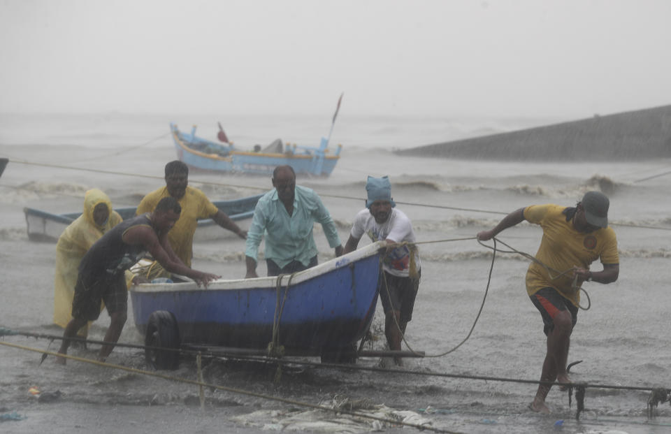 Fishermen try to move a fishing boat to a safer ground on the Arabian Sea coast in Mumbai, India, Monday, May 17, 2021. Cyclone Tauktae, roaring in the Arabian Sea was moving toward India's western coast on Monday as authorities tried to evacuate hundreds of thousands of people and suspended COVID-19 vaccinations in one state. (AP Photo/Rafiq Maqbool)