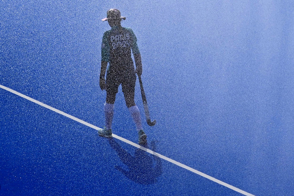 A ball girl walks along the center line before the start of the men's Group A field hockey match between South Africa and Germany