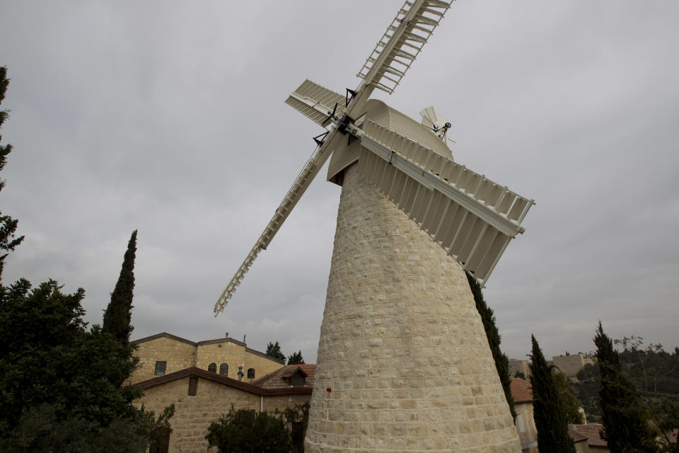 ADVANCE - This Thursday, Dec. 13, 2012 photo shows the Montefiore Windmill in Mishkenot Shaananim neighborhood in Jerusalem. Constructed in 1860 by Sir Moshe Montefiore, a wealthy British Jew, Mishkenot Sha’ananim was the first Jewish neighborhood built outside the Old City walls. Beyond its earthly past, Jerusalem has an impossible beauty with broad appeal. For residents and tourists, secular and religious souls, city slickers or nature lovers, there is always an unexplored alleyway, street corner or vista that will show you the city as you’ve never seen it before. (AP Photo/Ariel Schalit)