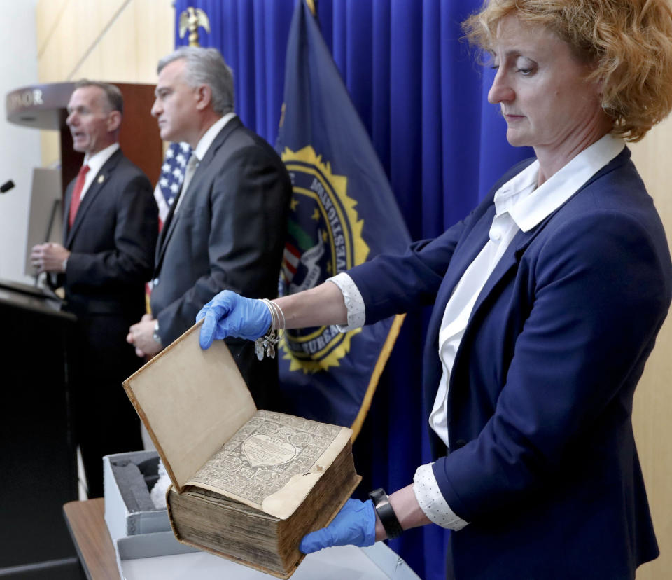 FBI Special Agent in Charge Robert Jones, left, and Allegheny County District Attorney Stephen Zappala, center, talk about the efforts and ultimate recovery of the Breeches Edition Bible that FBI supervisory special agent Shawn Brokos, right, holds during a news conference, Thursday, April 25, 2019, in Pittsburgh. The Bible that was published in 1615 was stolen from the Carnegie Library in Pittsburgh in the 1990's. It was traced to the American Pilgrim Museum in Leiden, Netherlands. (AP Photo/Keith Srakocic)