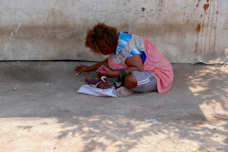 A woman smokes a cigarette as she sits outside a house in the area called Poreporena Villages in the city of Port Moresby, Papua New Guinea, November 19, 2018. Picture taken November 19, 2018. REUTERS/David Gray