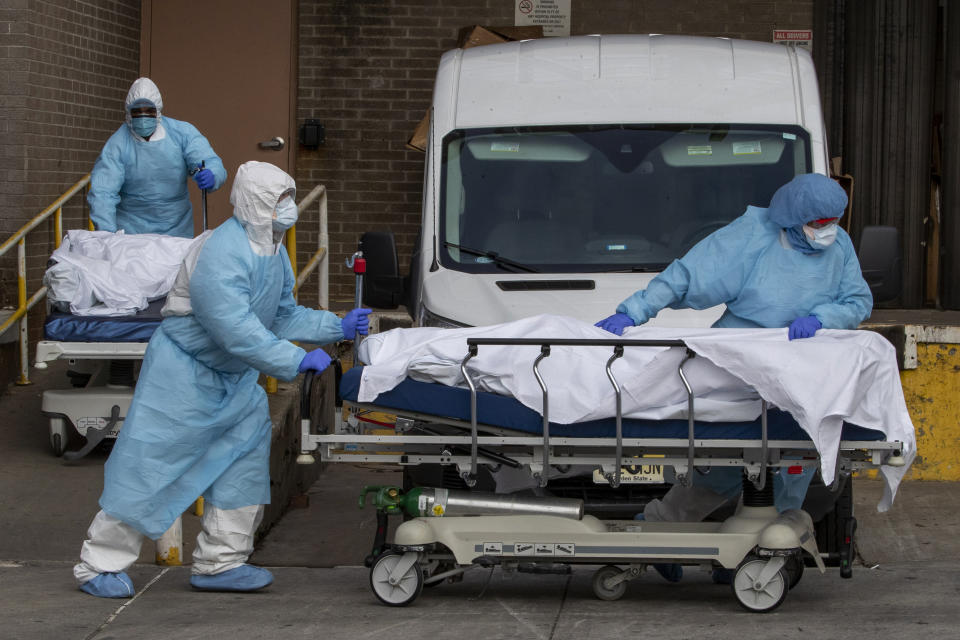 Medical personnel wearing personal protective equipment remove bodies from the Wyckoff Heights Medical Center Thursday, April 2, 2020 in the Brooklyn borough of New York. As coronavirus hot spots and death tolls flared around the U.S., the nation's biggest city was the hardest hit of the all, with bodies loaded onto refrigerated morgue trucks by gurney and forklift outside overwhelmed hospitals, in full view of passing motorists. (AP Photo/Mary Altaffer)