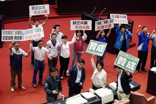 圖為立法院22日審查「國民法官法」草案，在通過二讀後，國民黨立委高舉標語並大喊「民進黨反對陪審，全民唾棄」，民進黨立委帶著笑容舉著「贊成」牌子。（資料照,姚志平攝）