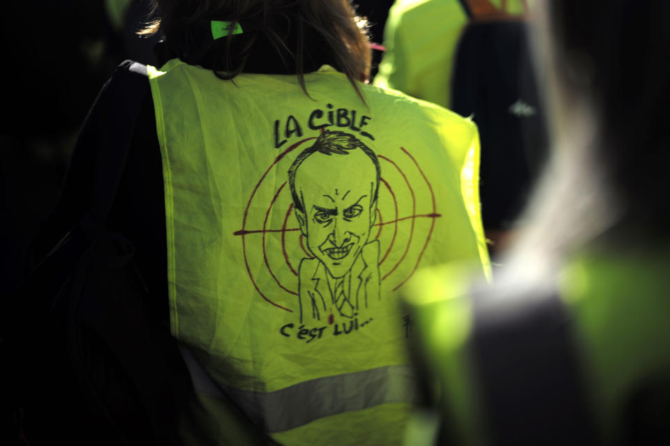 A protester wears a a yellow vest with a drawing depicting French President Emmanuel Macron and the word "target" during a de demonstration in the streets of Paris, France, Saturday, Feb. 23, 2019. French yellow vest protest organizers are trying to tamp down violence and anti-Semitism in the movement's ranks as they launch a 15th straight weekend of demonstrations. (AP Photo/Kamil Zihnioglu)