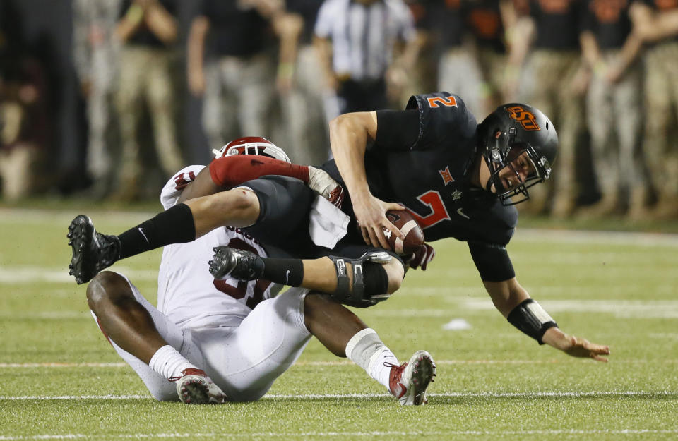 FILE - Oklahoma State quarterback Mason Rudolph (2) is sacked by Oklahoma defensive end Ogbonnia Okoronkwo, left, in the second half of an NCAA college football game in Stillwater, Okla., Nov. 4, 2017. Oklahoma and Oklahoma State will meet on Saturday for the final time before Oklahoma leaves the Big 12 for the Southeastern Conference. (AP Photo/Sue Ogrocki, File)