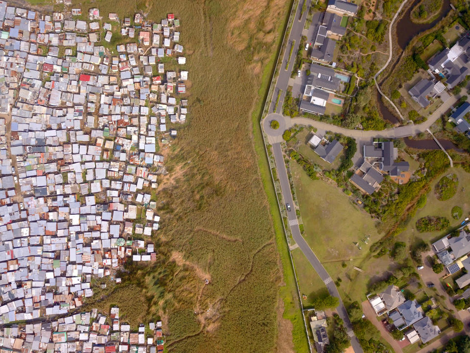 Aerial view contrasting dense informal housing with structured suburban homes, divided by a road