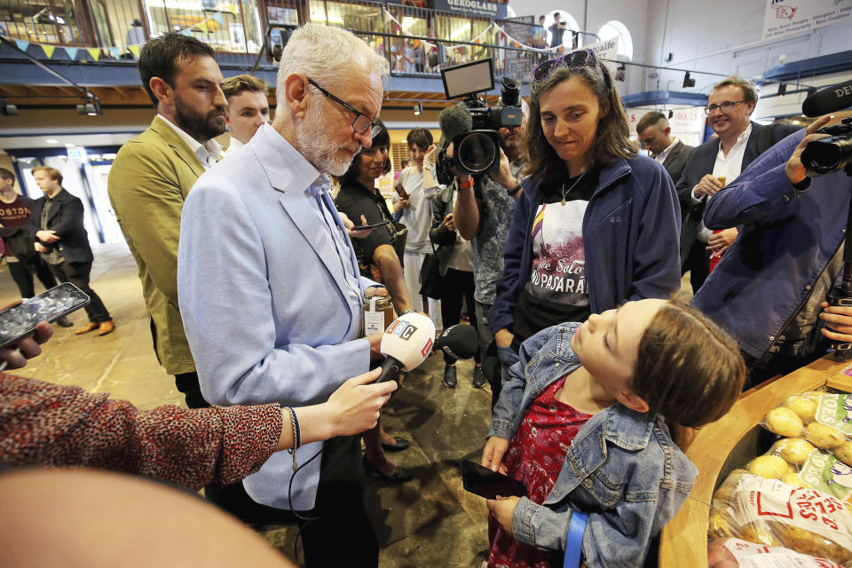 Britain's Labour leader Jeremy Corbyn speaks to a young girl, during a visit to Scarborough Public Market to discuss the impact of a no-deal Brexit on food bills, in Scarborough, England, Friday, Aug. 2, 2019. (Nigel Roddis/PA via AP)