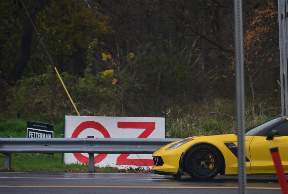A sportscar drives past a home made sign stating "OZ" beside a campaign yard sign stating "FETTERMAN" near the location where Republican senatorial candidate Dr. Mehmet Oz held a small business roundtable with U.S. Rep. Brian Fitzpatrick, R-Pa., and Sen. Susan Collins, R-Maine, at Washington Crossing Inn on Nov. 6, 2022 in Bucks County, Pennsylvania. Oz faces Democratic candidate John Fetterman in the general election on Nov. 8.