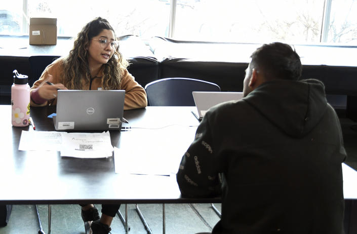 Miriam Jimenez, left, intake coordinator for Denver Human Services, speaks with a migrant at a makeshift shelter in Denver, Friday, Jan. 6, 2023. Over the past month, nearly 4,000 immigrants, almost all Venezuelans, have arrived unannounced in the frigid city, with nowhere to stay and sometimes wearing T-shirts and flip-flops. In response, Denver converted three recreation centers into emergency shelters for migrants and paid for families with children to stay at hotels, allocating $3 million to deal with the influx. (AP Photo/Thomas Peipert)