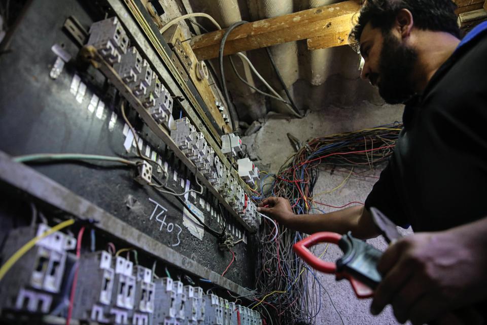 Kadim Aboud, a worker in a private electricity generating company, turns the switches to transfer electricity to private homes in Basra, Iraq, Tuesday, June. 29, 2021. A widespread power outage is hitting Iraq as temperatures reach scorching levels, affecting even affluent areas in the capital and stirring concerns of widespread unrest. (AP Photo/Nabil al-Jurani)