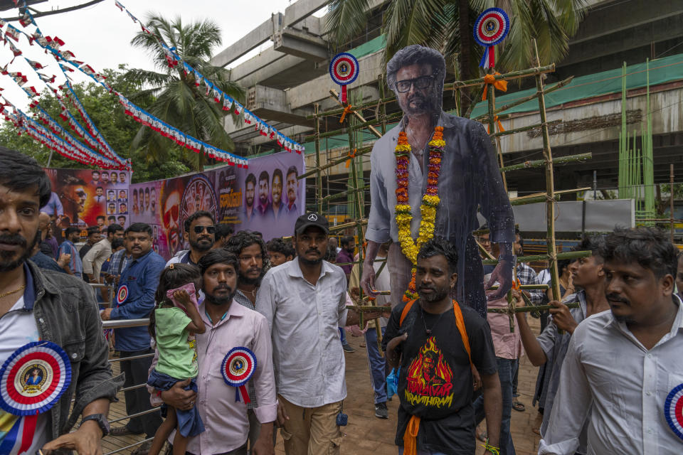 Indian fans carry a cutout of their superstar Rajinikanth as they arrive to watch the screening of his latest film "Jailer" in Mumbai, India, Thursday, Aug. 10, 2023. (AP Photo/Rafiq Maqbool)