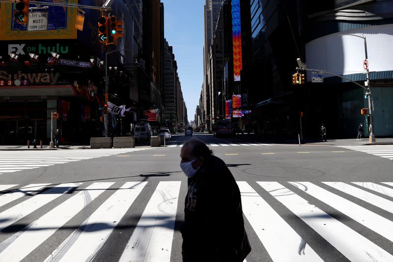 A man crosses 7th Avenue in nearly deserted Times Square during the outbreak of the coronavirus disease (COVID-19) in New York