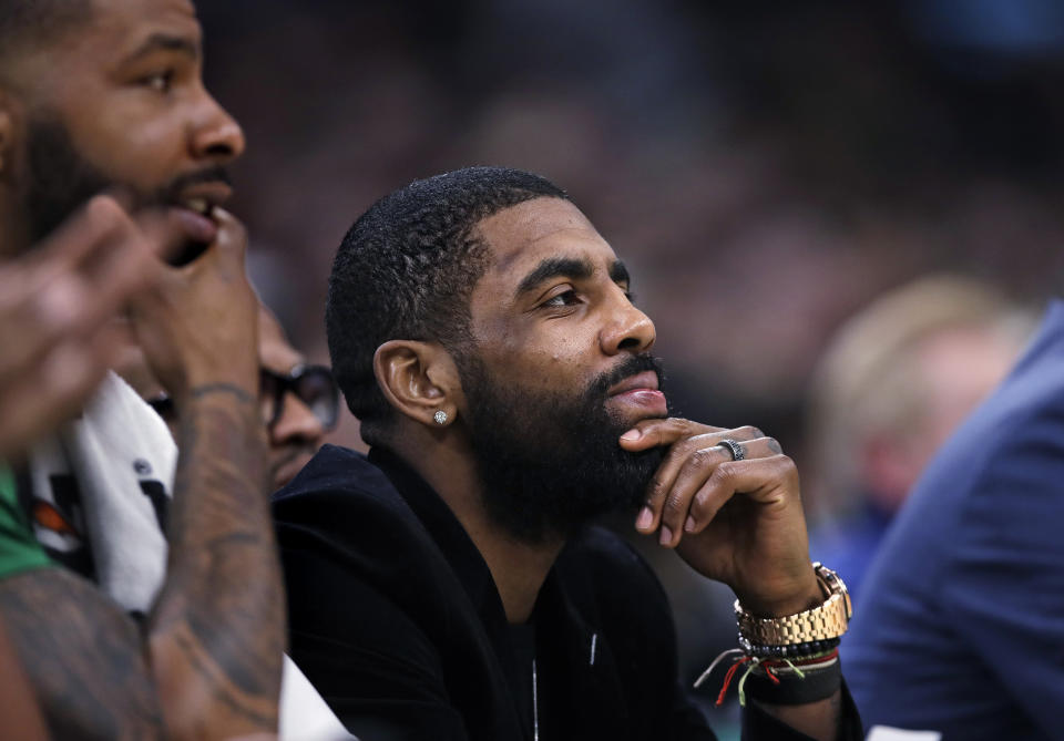 Boston Celtics guard Kyrie Irving, center, who is sidelined with a hip strain, watches play from the bench with forward Marcus Morris, left, during the first quarter of the team's NBA basketball game against the Charlotte Hornets in Boston, Wednesday, Jan. 30, 2019. (AP Photo/Charles Krupa)