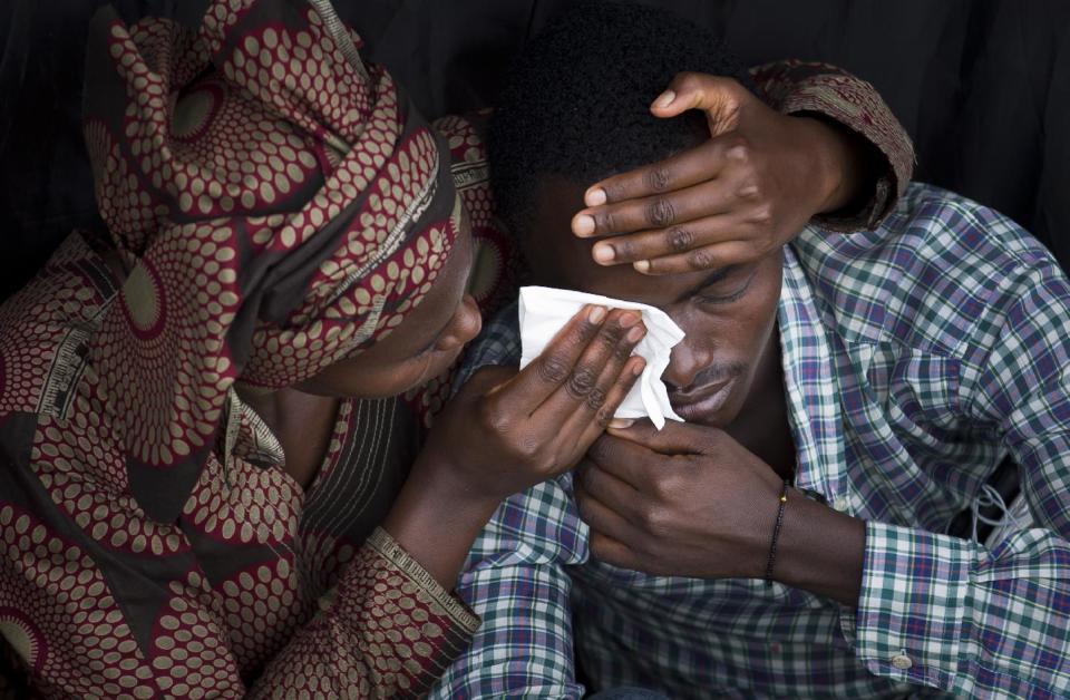 Bizimana Emmanuel, who was born two years before the genocide, is consoled by an unidentified woman while attending a public ceremony to mark the 20th anniversary of the Rwandan genocide, at Amahoro stadium in Kigali, Rwanda, Monday, April 7, 2014. Sorrowful wails and uncontrollable sobs resounded Monday as thousands of Rwandans packed the country's main sports stadium to mark the 20th anniversary of the beginning of a devastating 100-day genocide. (AP Photo/Ben Curtis)