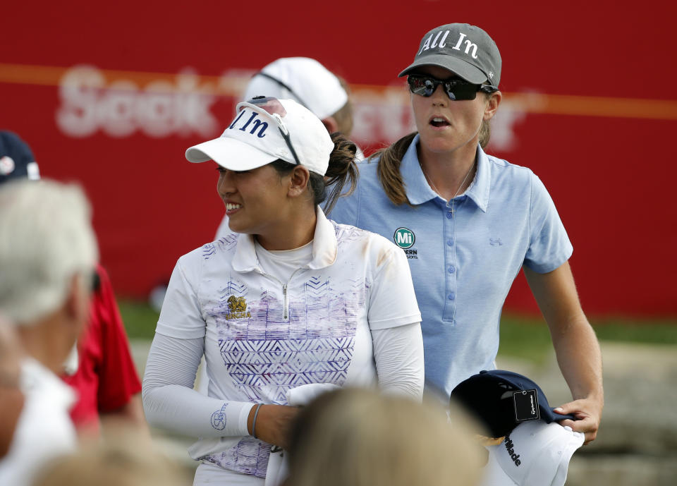 Jasmine Suwannapura, left, ant teammate Cydney Clanton hand out caps to fans as they walk off the 18th tee during the third round of the Dow Great Lakes Bay Invitational golf tournament, Friday, July 19, 2019, in Midland, Mich. (AP Photo/Carlos Osorio)