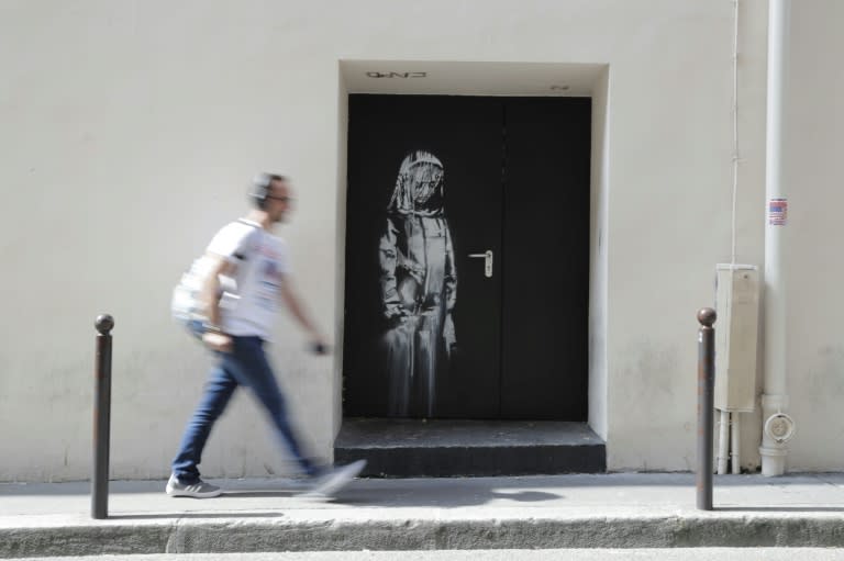 A man walks past an image of a woman apparently in mourning by Banksy on a side street around the corner from the Bataclan concert hall in Paris where jihadists killed 90 people in November 2015