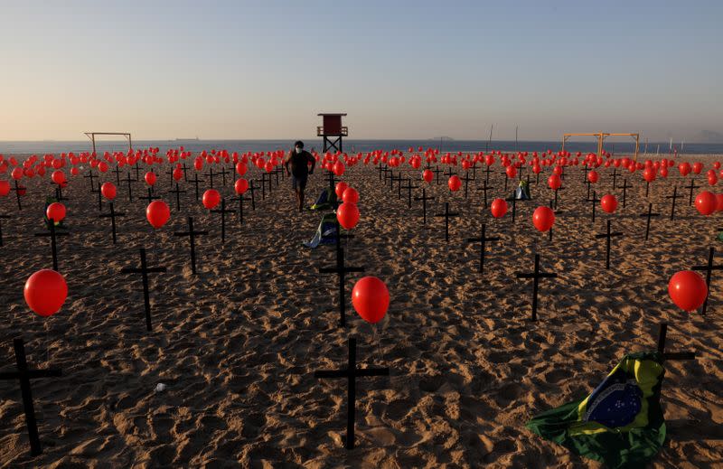 Una persona entre las cruces y globos colocados por miembros de la ONG Río de Paz en homenaje a las cien mil víctimas mortales de la enfermedad COVID-19 en el país, en la playa de Copacabana en Río de Janeiro