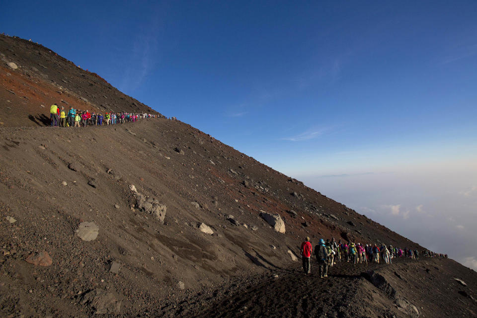 In this Sunday, Aug. 11, 2013 photo, hikers make their way down from the summit of Mount Fuji after watching the sunrise form the top. The recent recognition of the 3,776-meter (12,388-foot) peak as a UNESCO World Heritage site has many here worried that will draw still more people, adding to the wear and tear on the environment from the more than 300,000 who already climb the mountain each year. (AP Photo/David Guttenfelder)
