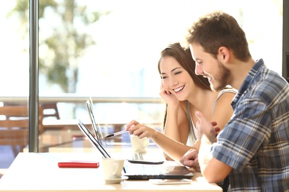 Man and woman pointing at a laptop and smiling