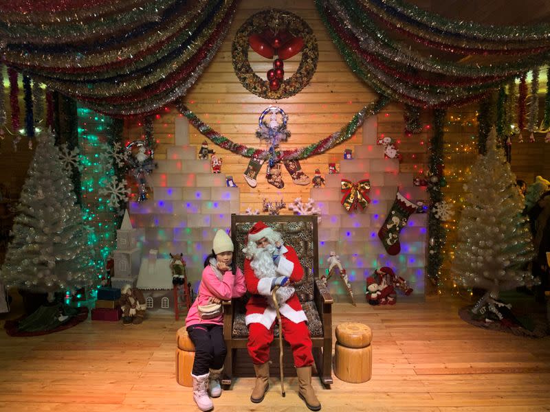 Visitor poses with a Santa, played by Ville Haapassallo from Finland, inside the Santa Claus House at a Christmas theme park on the outskirts of Mohe, China's northernmost city in Heilongjiang province
