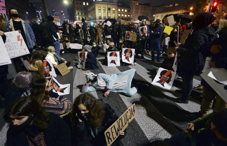 Protesters block a crossing in downtown Warsaw, Monday, Nov. 9, 2020, on the 12th straight day of anti-government protests that were triggered by the tightening of Poland's strict abortion law and are continuing despite a anti-COVID-19 ban on public gatherings. (AP Photo/Czarek Sokolowski)