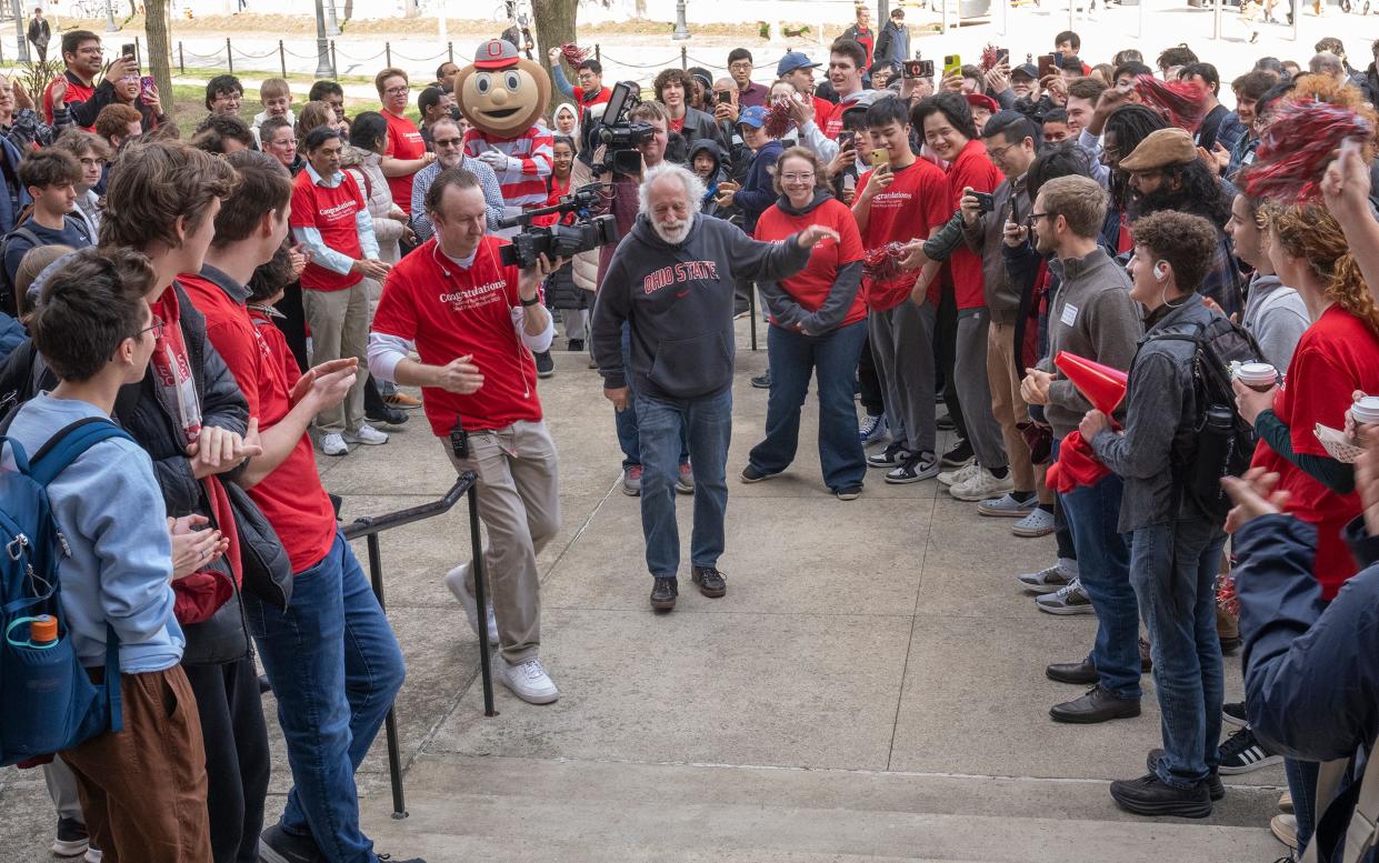 Nobel laureate Pierre Agostini is welcomed by students and staff Wednesday as he returns for a visit to the Ohio State University Physics Research building. Agostini, an Ohio State professor emeritus, donated a 24-karat gold replica of his Nobel Prize to the university, which plans to make it part of a permanent display in the building's lobby.