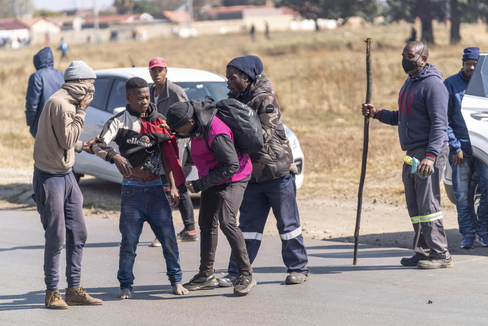 Residents grab a man suspected of being an illegal miner in the South African city of Krugersdorp Thursday Aug. 4, 2022. Community members in the assaulted suspected illegal miners and set fire to their camps on Thursday in an outpouring of anger following the alleged gang rapes of eight women by miners last week. Residents of Krugersdorp's Kagiso township also barricaded roads with rocks and burning tires during a planned protest. (AP Photo/ Shiraaz Mohamed)