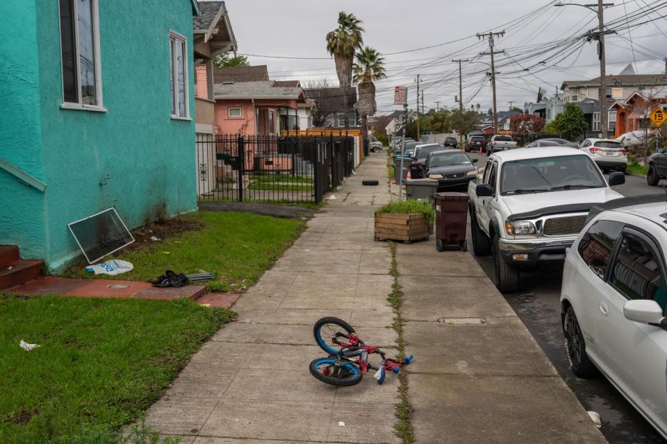 A child's bicycle rests on a sidewalk.