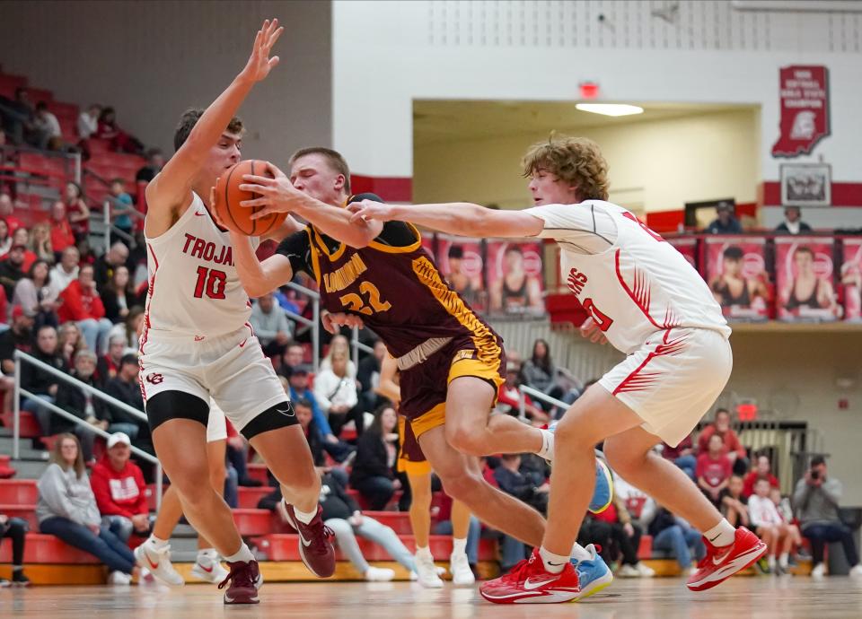Bloomington North’s Luke Lindeman (22) drives to the basket against Center Grove’s Ben Chestnut (10) and Gabe Baxter (20) during their game at Center Grove on Friday, Dec. 1, 2023.