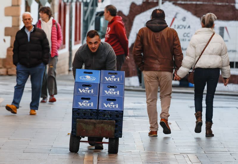 Un repartidor empuja un carro con cajas de botellas de agua en Ronda