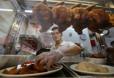 Hawker Derrick Lee, 30, sells chicken rice in his stall at a hawker centre in Singapore June 30, 2016. REUTERS/Edgar Su