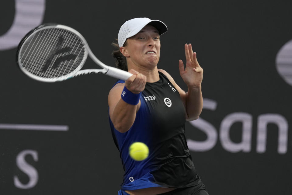 Iga Swiatek, of Poland, returns the ball during a women's singles final of the WTA Finals tennis championships against Jessica Pegula, of the United States, in Cancun, Mexico, Monday, Nov. 6, 2023. (AP Photo/Fernando Llano)