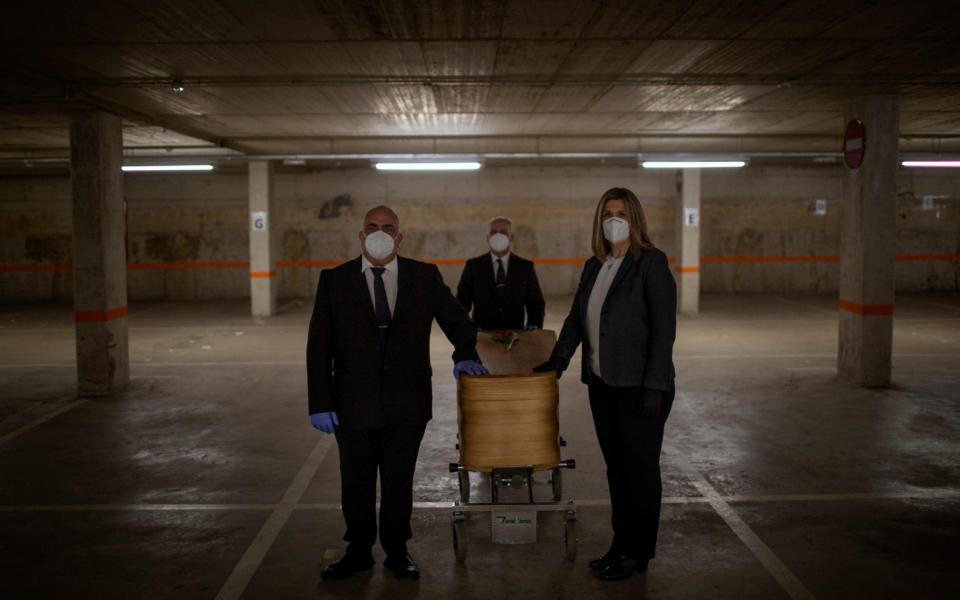 Mortuary service workers carry the coffin of the last COVID-19 victim stored at an underground parking garage that was turned into a morgue, at the Collserola funeral home in Barcelona.   - Emilio Morenatti/AP 