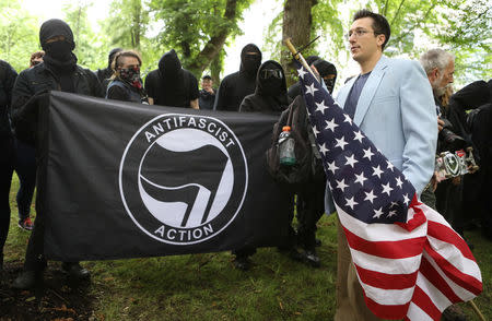 A conservative protester (R) walks past a group of anti-fascist during competing demonstrations in Portland, Oregon, U.S. June 4, 2017. REUTERS/Jim Urquhart