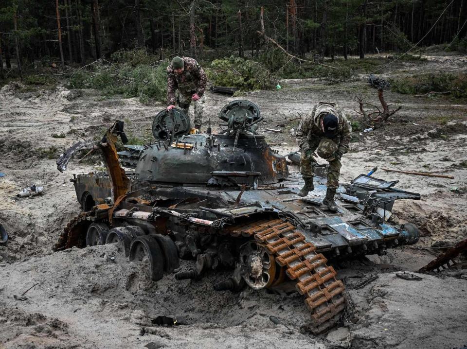 Ukrainian troops inspect a destroyed Russian tank